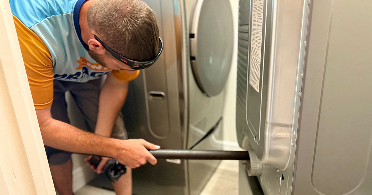 Dryer vent technician cleaning rear vent on dryer