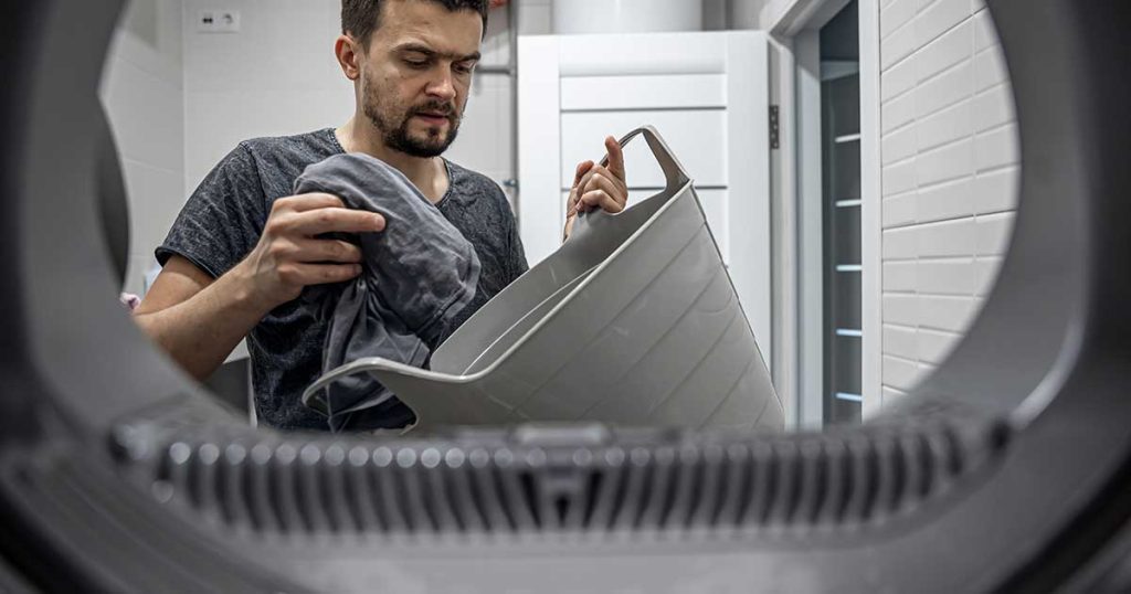 A man loading laundry into a dryer