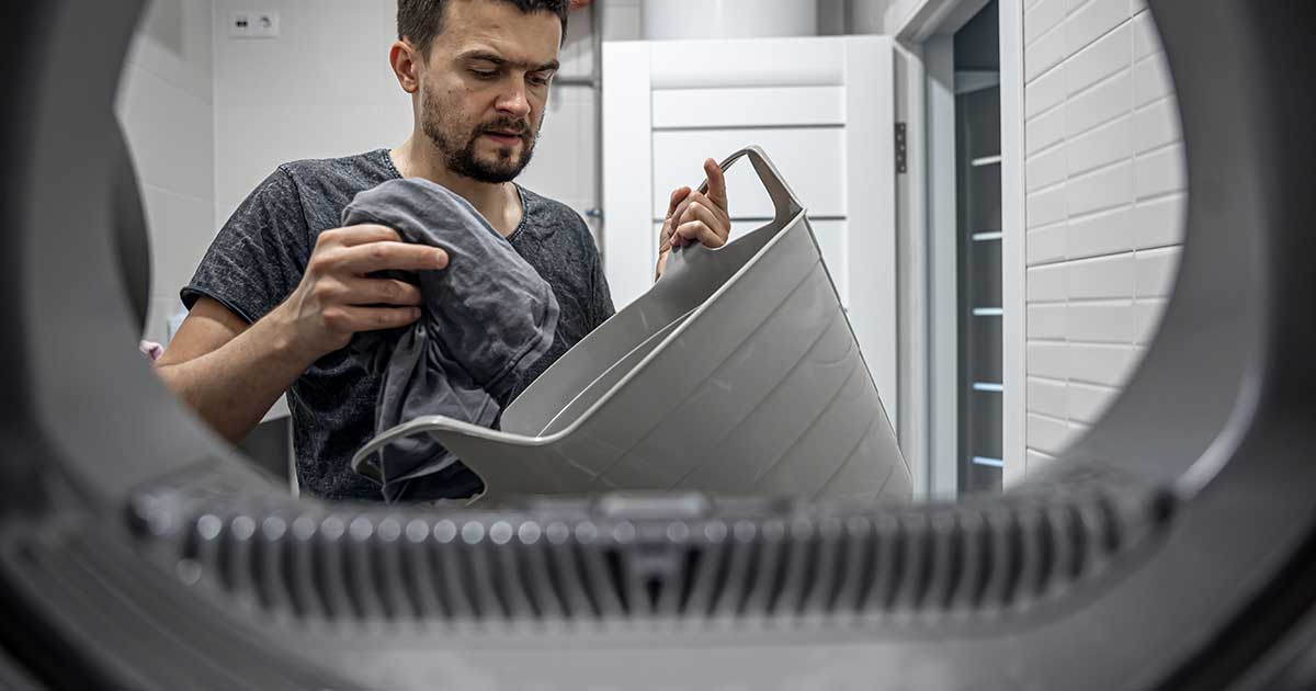 A man loading laundry into a dryer